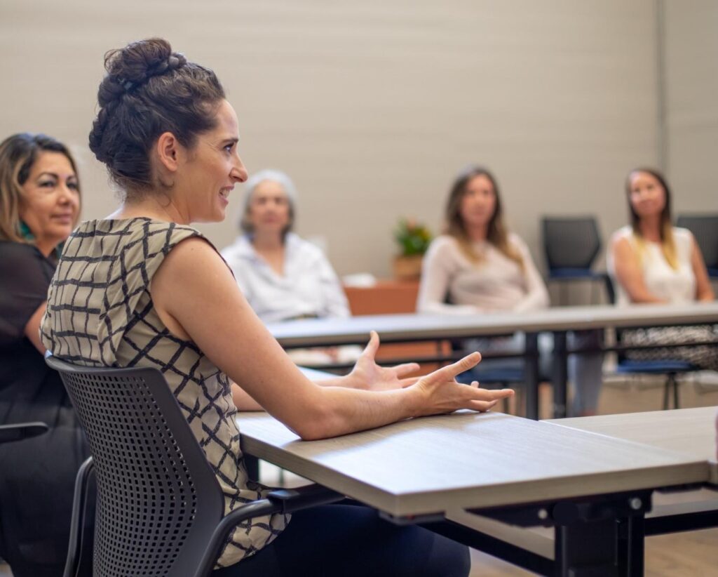 Community member, Kelly Almeida, and classmates discuss business planning in a WEV business class.