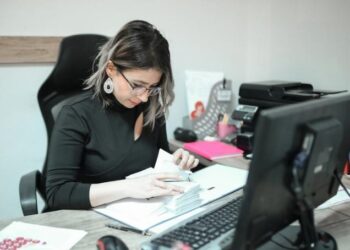 Propietaria de negocio sentada en un escritorio revisando libros en busca de errores