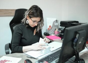 Business owner sitting at a desk reviewing books for accounting mistakes