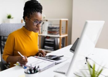 Business owner sitting at a computer, maintaining business bookkeeping records