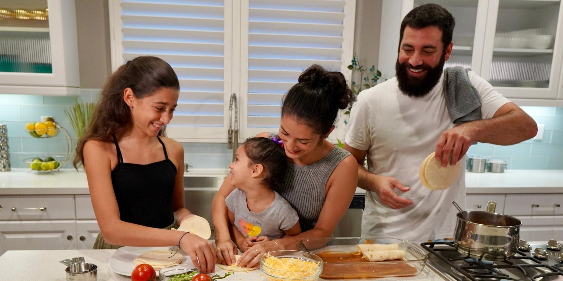 Jessica Mickey, clienta de WEV, y su esposo Sean cocinan con sus hijas para su negocio, Wundercooks